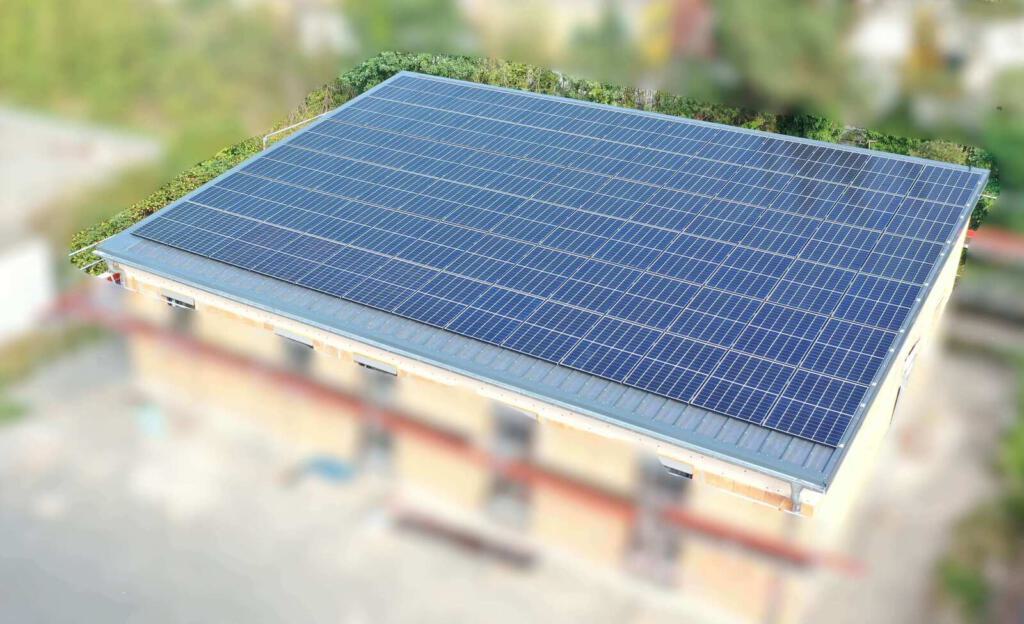 Eine große Photovoltaikfläche auf dem Dach eines Gebäudes, aus der Vogelperspektive aufgenommen.