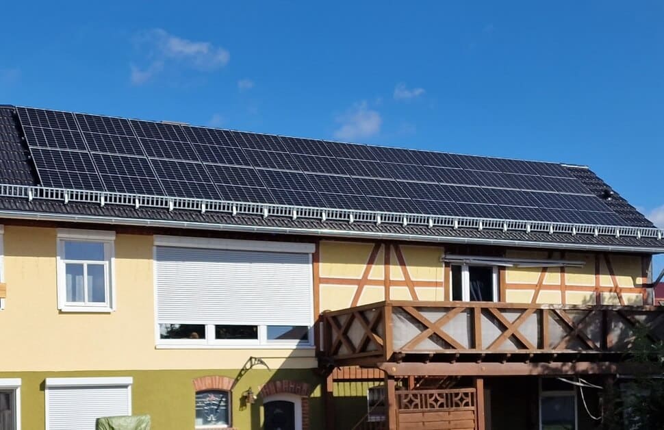 Ein Wohnhaus mit einer großflächigen Photovoltaikanlage auf dem Dach, aufgenommen bei sonnigem Wetter.